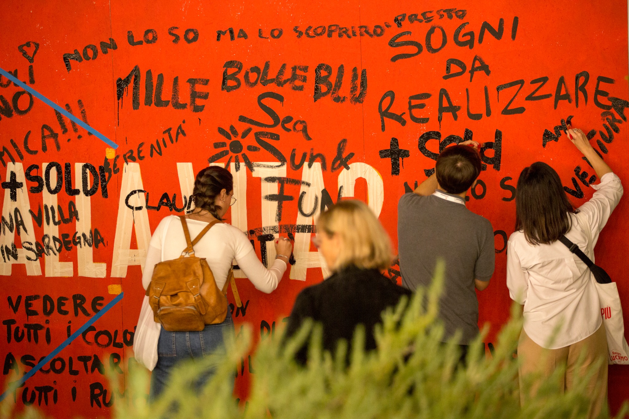 Partecipanti al seminario di Museimpresa che scrivono frasi su di una parete rossa